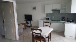 eine Küche mit weißen Schränken sowie einem Tisch und Stühlen in der Unterkunft Petite maison au cœur du Berry in Culan
