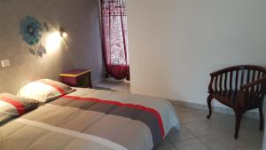 a bedroom with a bed and a chair and a window at Petite maison au cœur du Berry in Culan