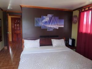 San IsidroにあるSailfishbay Surf And Big Game Fishing Lodgeの白いベッド1台、壁に絵画2点が備わるベッドルーム1室