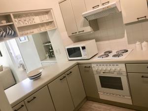 a white kitchen with a stove and a microwave at On The Square Luxury Apartment in Simonʼs Town