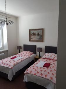 a bedroom with two beds with red and white sheets at Pension U Dolezalu in Brno