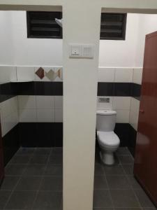 a bathroom with a toilet and black and white tiles at ROSA Motel in Pantai Cenang +1 photo