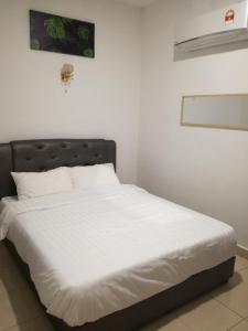 a bed with white sheets and a black headboard at ROSA Motel in Pantai Cenang