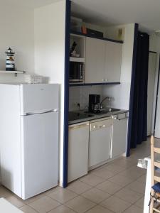 a kitchen with white cabinets and a white refrigerator at Appartement vue sur golf in Talmont
