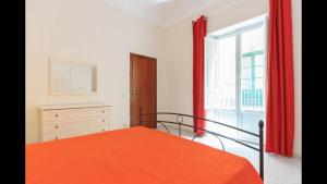 a bedroom with an orange bed and a window at Spacious modern and cozy apartment in Trapani