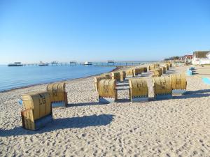 a row of benches on a beach near the water at Ferienwohnungen & Bungalows Waldstraße 15 Kellenhusen in Kellenhusen