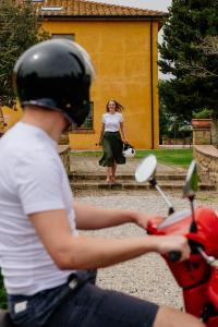 Una donna che cammina davanti a una donna su uno scooter rosso di Villa Aia Vecchia a Bibbona