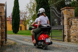 twee mensen op een rode scooter op een oprit bij Villa Aia Vecchia in Bibbona