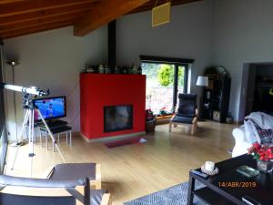sala de estar con chimenea roja y TV en La Riega del Peral, en Ojedo