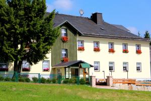 a large white house with red flowers on the windows at Landhaus Sonnentau in Johanngeorgenstadt
