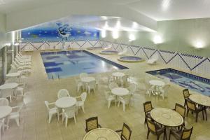 a pool with tables and chairs and a swimming pool at Capivari Ecoresort in Campina Grande do Sul