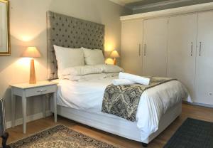 Un dormitorio con una gran cama blanca con cabecero. en Lavender Suite, en Ciudad del Cabo