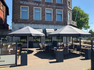 a patio with tables and umbrellas in front of a building at Hotel Wilhelmina in Venlo