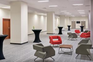 a waiting room with red chairs and tables at Metropolo by Golden Tulip Krakow in Kraków