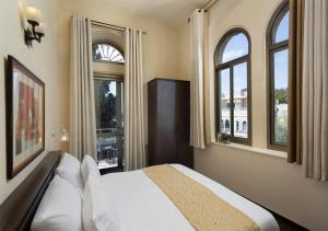 a bedroom with a bed and two windows at The Little House In Bakah in Jerusalem