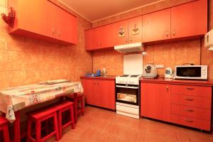 a kitchen with red cabinets and a white stove top oven at Szarvas Vendeghaz in Izvoru Mureşului