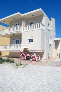 uma carruagem vermelha puxada por cavalos estacionada em frente a uma casa em Mithos Premium Rooms em Agia Marina Nea Kydonias