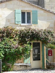 a building with a door and a bush with flowers at Les Oiseaux in Saint-Émilion