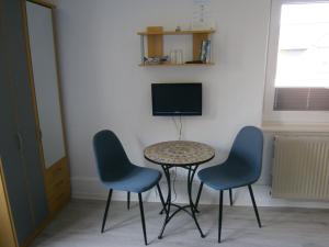 einen Tisch und zwei Stühle sowie einen TV in einem Zimmer in der Unterkunft Haus Steinbach in Kellenhusen