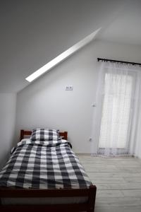 a bedroom with a bed with a checkered blanket at LENIÓWKA in Ponikiew
