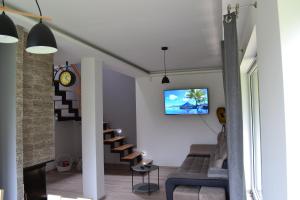 a living room with a couch and a tv on the wall at LENIÓWKA in Ponikiew