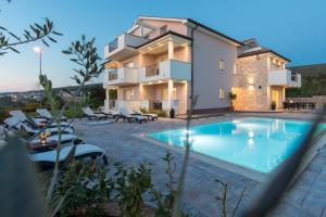 a villa with a swimming pool in front of a house at B&B Villa Maris in Punat