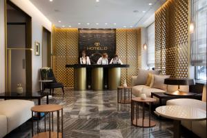 3 Personen sitzen an einer Bar in einer Hotellobby in der Unterkunft Hotel D Geneva in Genf