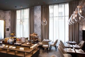 a dining room with tables and chairs and windows at Hotel D Geneva in Geneva