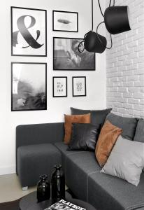 a living room with a gray couch and pictures on the wall at Sopot Hills - White Apartment in Sopot