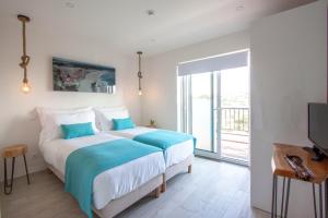 een slaapkamer met een groot bed en een televisie bij Hillside House Suites & Spa in Foz do Arelho