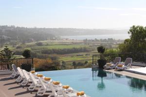 a swimming pool with white lounge chairs and a view at Hillside House Suites & Spa in Foz do Arelho