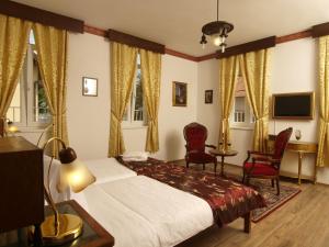 a bedroom with a bed and two chairs and a television at Hotel Puntijar in Zagreb