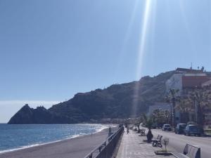 a beach with a bridge and the ocean and a mountain at SANT'ALESSIO BEACH HOLIDAY in SantʼAlessio Siculo