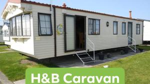 a white house with a sign that reads hbc caravan at H&B Caravan on Marine Holiday Park in Rhyl