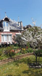a house with a flowering tree in a yard at Vacances Paisibles Sur La Côte Fleurie. in Trouville-sur-Mer
