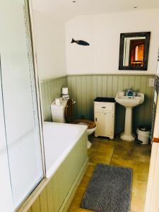a bathroom with a tub and a toilet and a sink at The Barn, Higher Boden, Manaccan, Helston, Cornwall in Helston