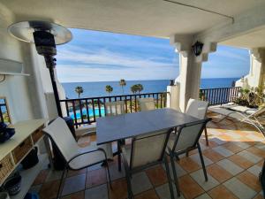 una mesa y sillas en un balcón con vistas al océano en Rocas del mar - Casa Remo, en Costa del Silencio