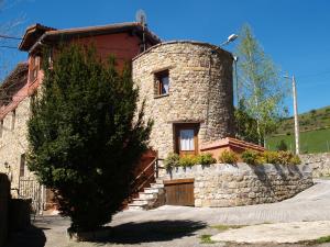 uma casa de pedra com uma árvore em frente em Albergue La Torre em Santiurde de Reinosa