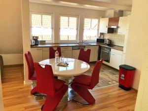 cocina con mesa de comedor y sillas rojas en Müritz Apartments in Waren Müritz en Waren