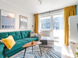 a living room with a green couch and a table at Apartament KAJA SurfingBird Kołobrzeg in Kołobrzeg