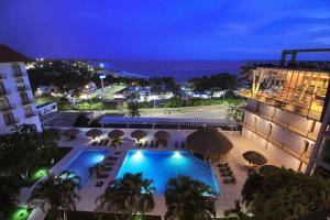 a view of a hotel with a swimming pool at night at Hotel Caracol Plaza in Puerto Escondido