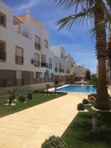 einen Apartmentkomplex mit einem Pool und einer Palme in der Unterkunft Gomeira Top Floor in Cabanas de Tavira