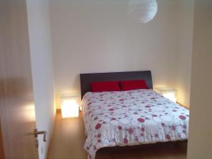 a bedroom with a bed with red pillows and two lights at Ericeira - Apartment with Patio - Horizonte Mar in Ericeira