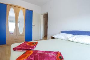 a bedroom with a white bed with a red blanket on it at SENITA's Rooms & Apartments in Nin