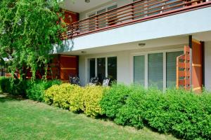 a house with a balcony and some bushes at Apartment Aurora in Moravske Toplice
