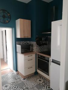 a kitchen with white cabinets and a clock on the wall at The Clock House, 3 étoiles in La Rochelle