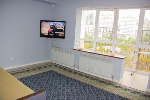 Hostel - Guest House Meyman في ألماتي: غرفة معيشة مع تلفزيون بشاشة مسطحة على الحائط
