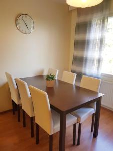 a dining room table with chairs and a clock on the wall at Home Away Holiday in Kuopio