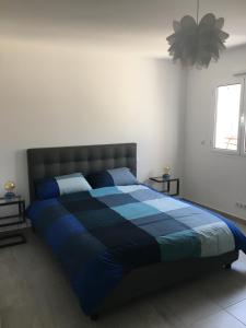 un letto in una camera da letto con un piumone blu di Charmant T2 Hauteurs de Bastia a Bastia