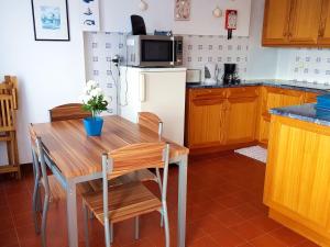 a kitchen with a wooden table and a refrigerator at Farol da Vila in Vila Franca do Campo